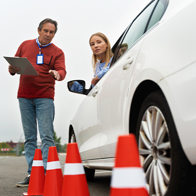 Profesor autoescuela explica a alumna